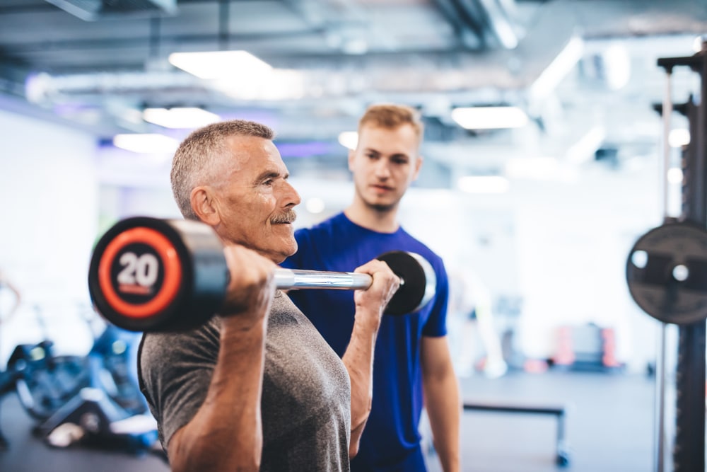 Older man working with personal trainer to prevent injuries while working out.