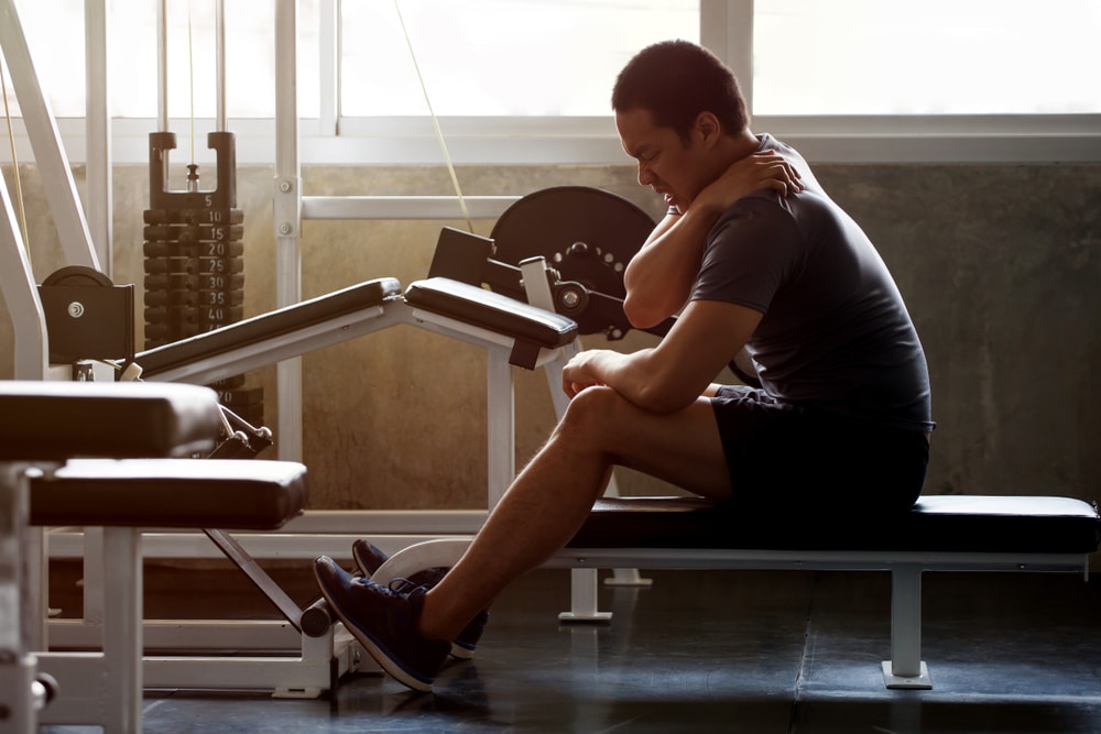 Man holding shoulder in pain during weight lifting session