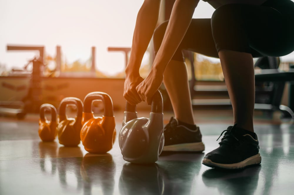 Woman picking up kettlebell during HIIT workout.