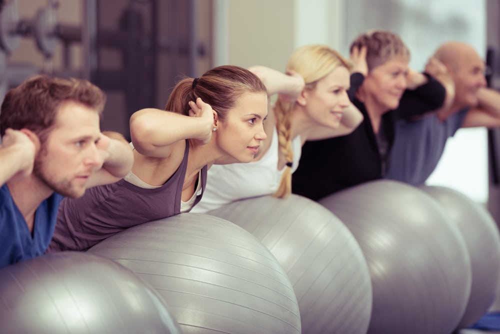 People in a pilates class doing core work on exercises balls