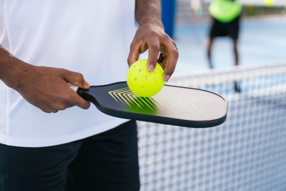 Man holding pickleball paddle and ball, ready for his first pickleball lesson.