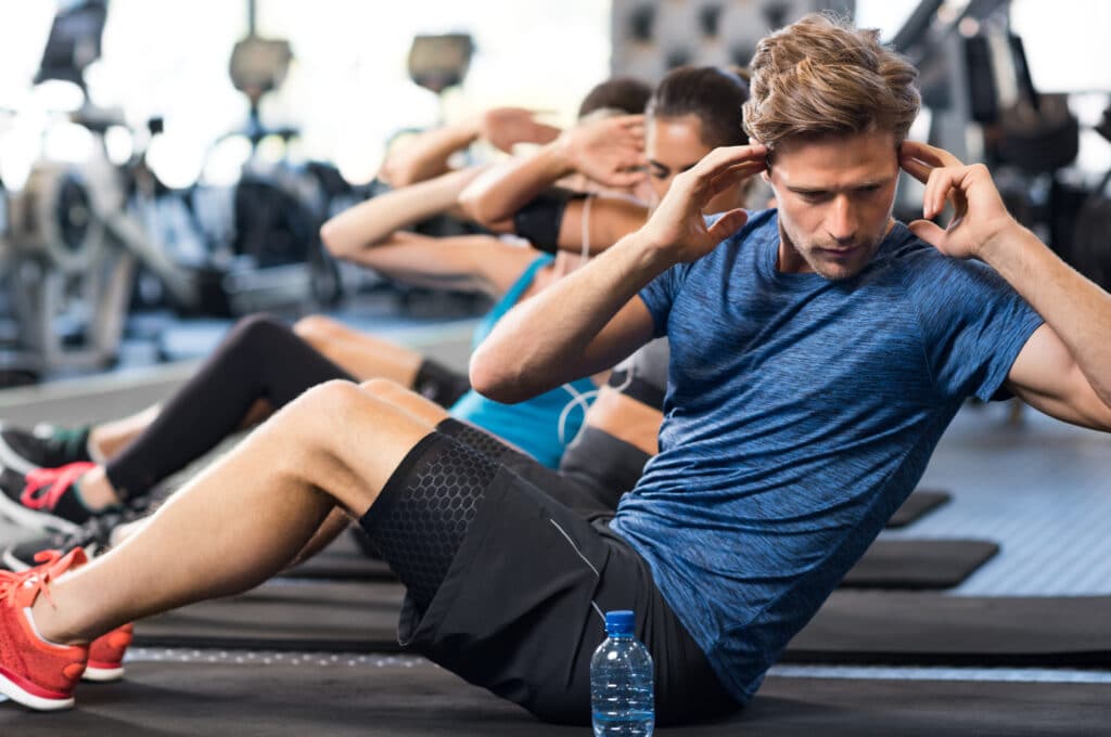 Group of people doing ab exercises on the floor at a gym to strengthen core