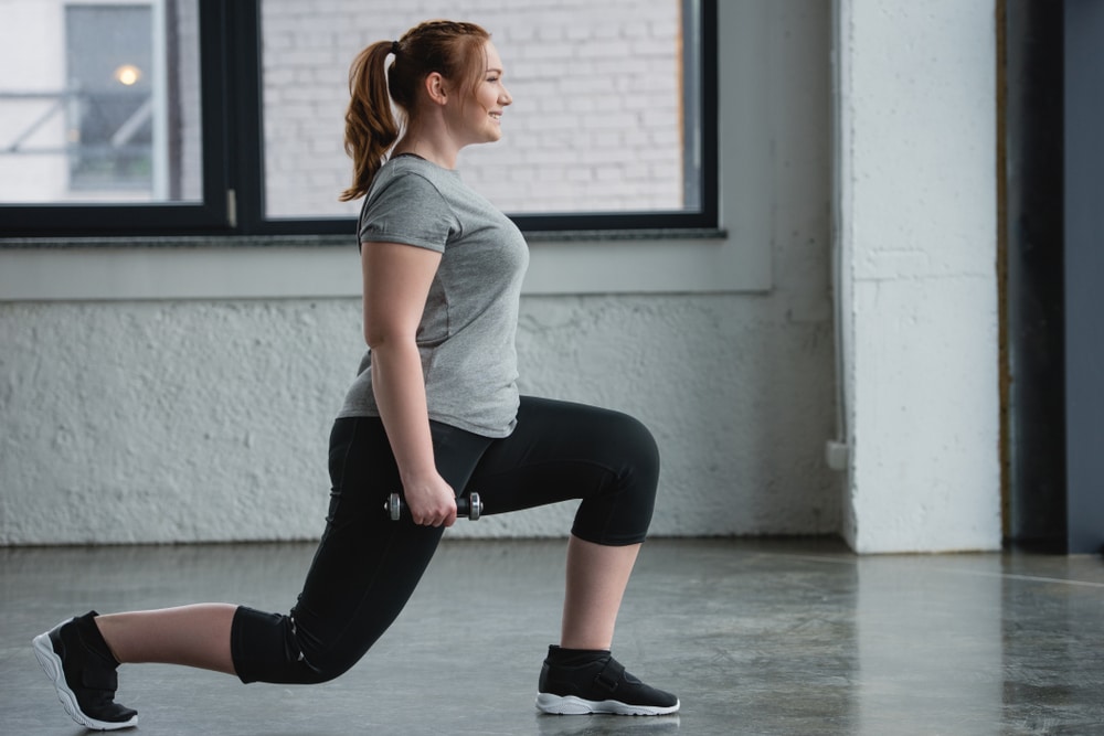 Woman doing lightly weighted lunges for strength training at gym